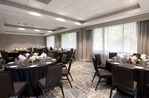 A conference room with round tables, chairs, and floral centerpieces.