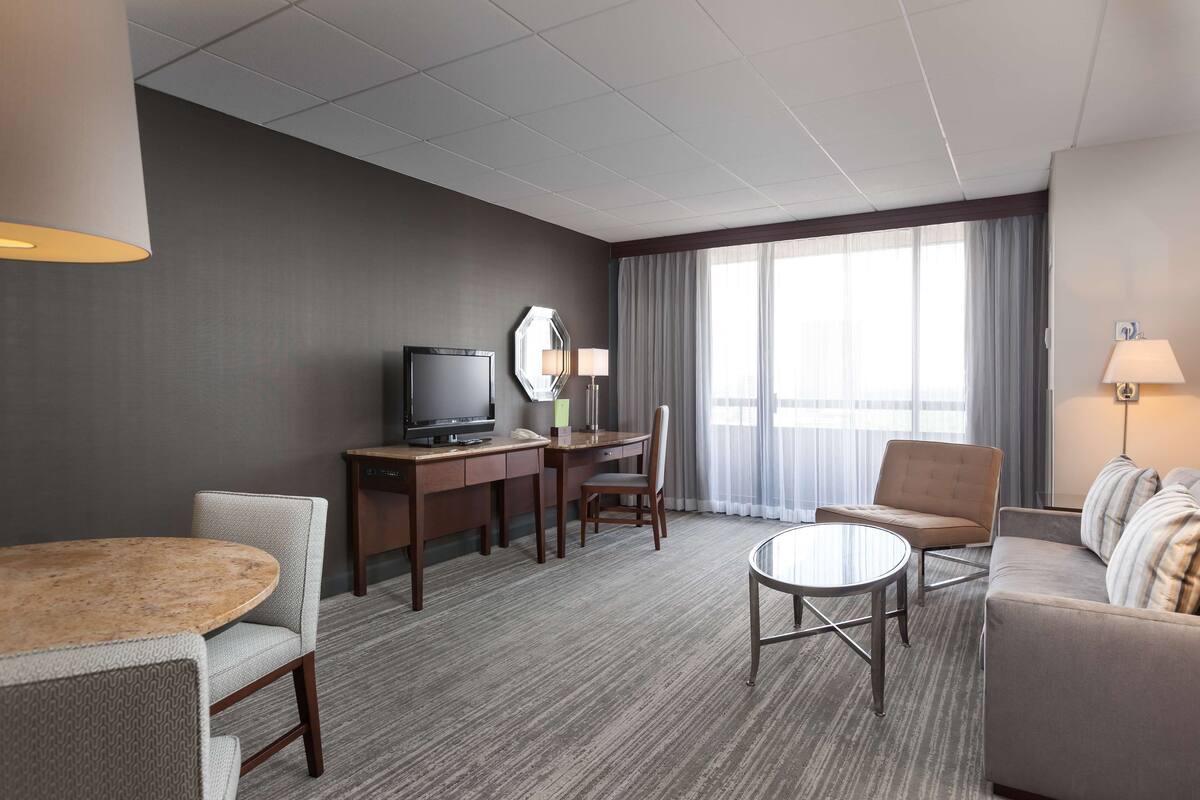 Habitación de hotel con escritorio, televisor y zona de estar.