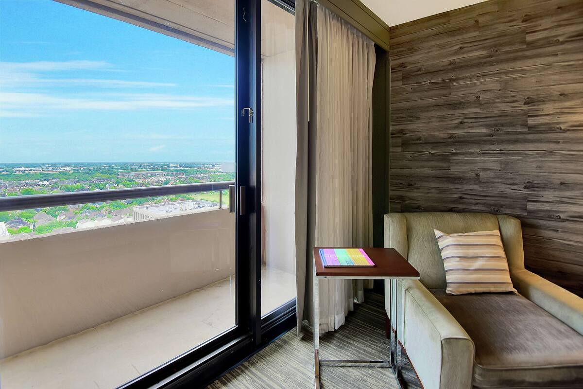 Un balcón con vistas a un paisaje urbano, un sofá, una mesita y una pared de madera.