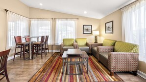 Un salon avec un canapé, des fauteuils, une table basse et un tapis.