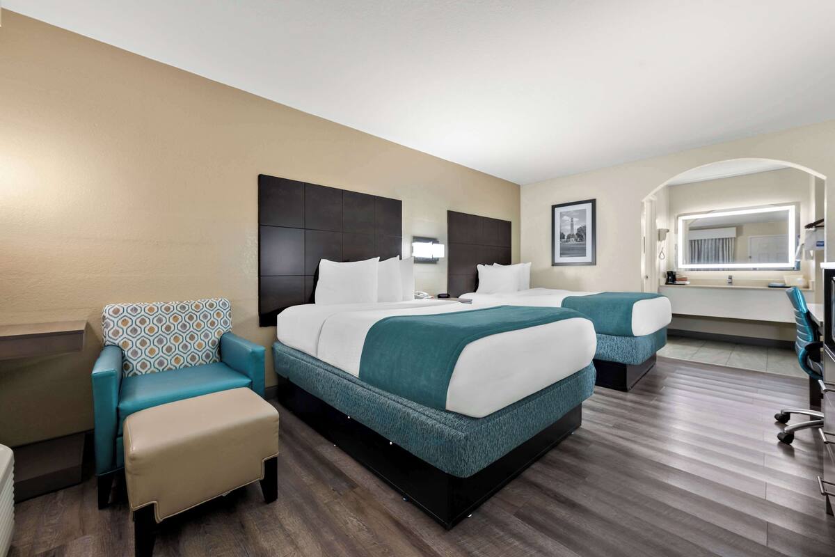 A hotel room with a large bed, two bedside tables, a chair, a desk, and a mirror.