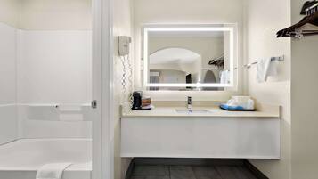 A modern bathroom with a bathtub, a sink with a mirror, and a towel rack.