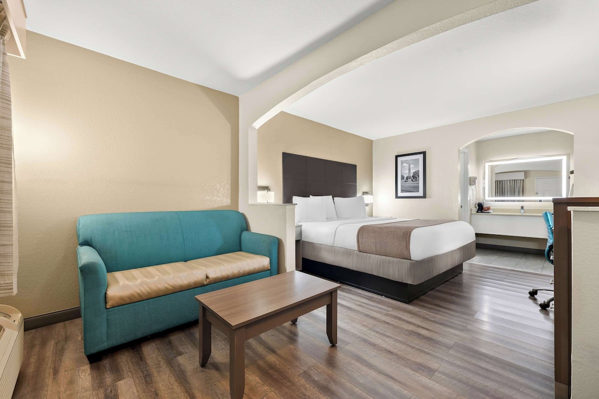 A hotel room with a bed, a sofa, a coffee table, and a desk.