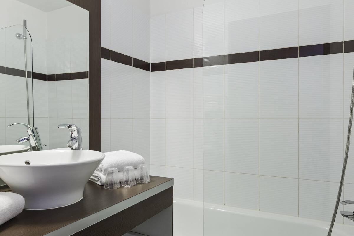A bathroom with a white sink, a mirror, a towel, and a shower.