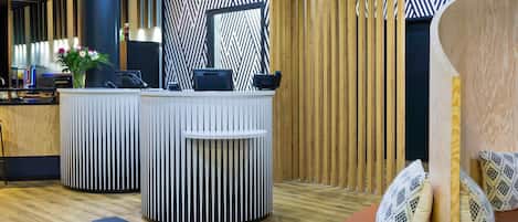 A reception area with two counters, a wooden slatted wall, and a seating area with patterned cushions.