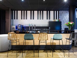 A bar area with a counter, stools, a television, and a decorative wall.