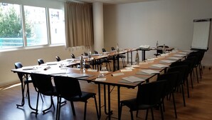Une salle de conférence avec une longue table, des chaises, des bouteilles d’eau et un tableau blanc.