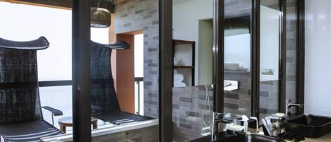 Un baño moderno con un espejo grande, lavamanos negros y un perchero para toallas.