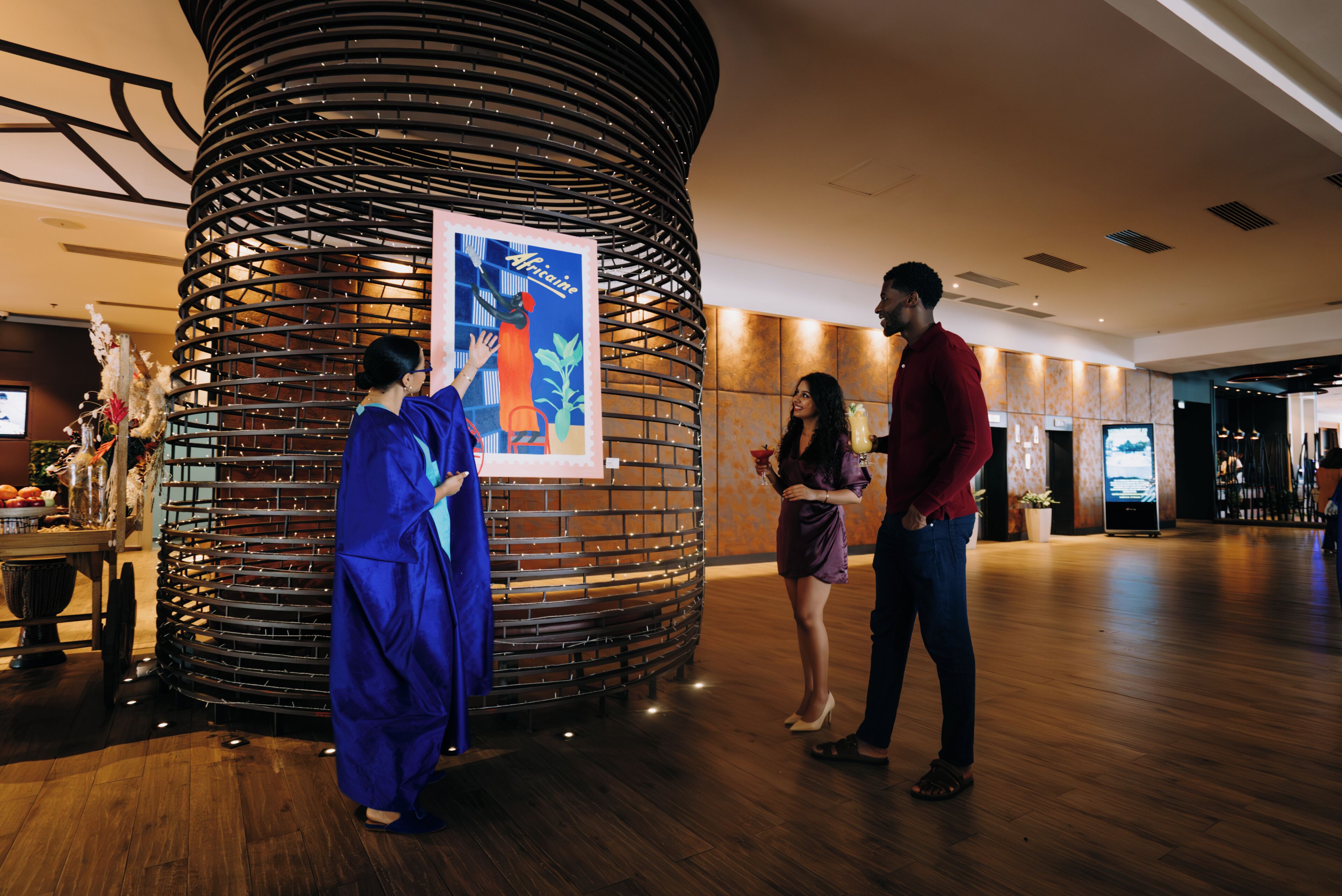 A hotel lobby with a large decorative column, a reception desk, and a television screen.