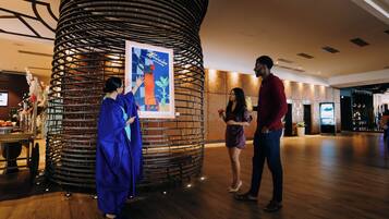 Un vestíbulo de hotel con una gran columna decorativa, una recepción y una pantalla de televisión.