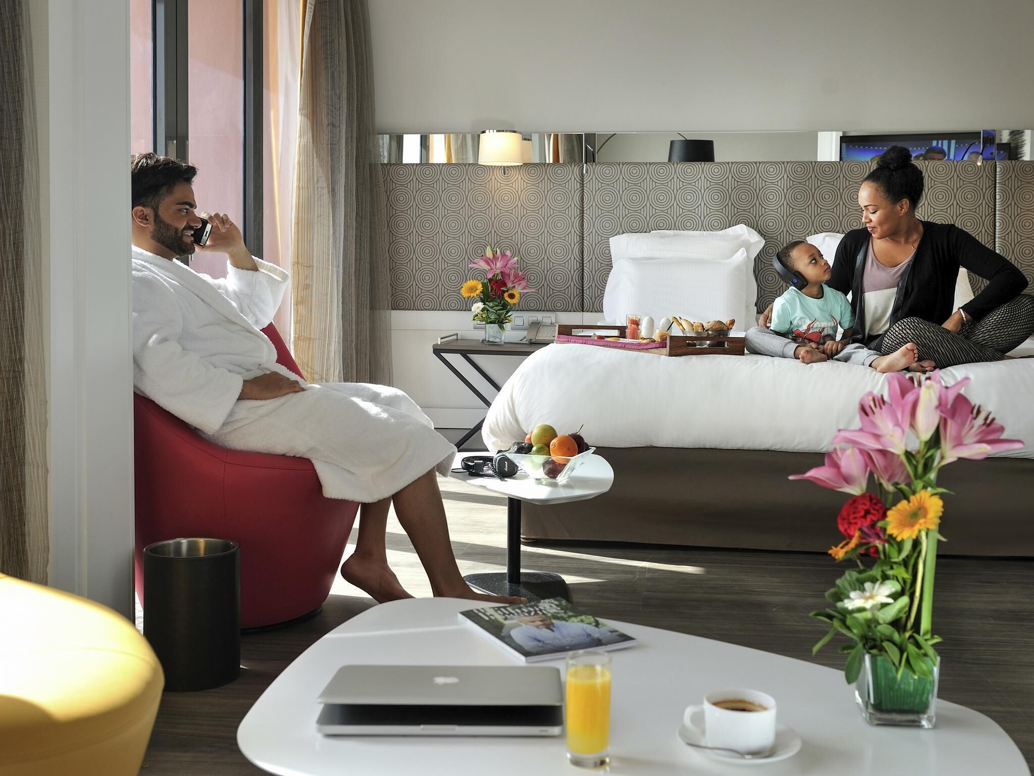 Une chambre d’hôtel avec un lit, un coin salon comprenant une table, un ordinateur portable et une tasse à café.