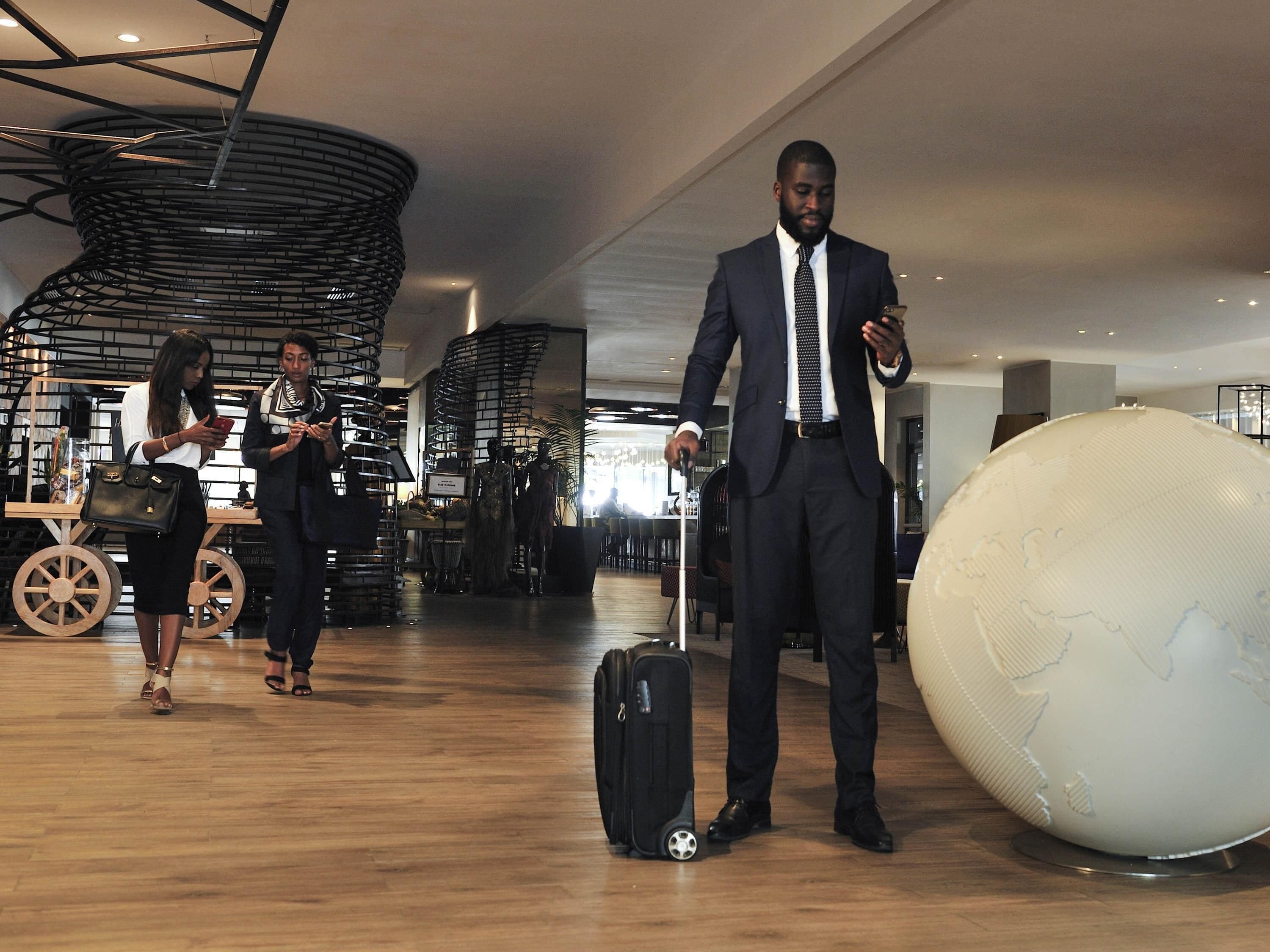 Un intérieur moderne avec un grand globe terrestre, un chariot à bagages et une personne en costume.