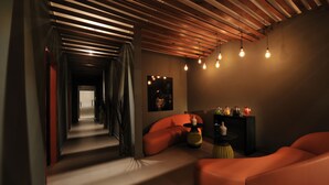A modern interior with a wooden ceiling, a hallway leading to a door, and orange seating areas. - Pullman Dakar Teranga (Dakar)