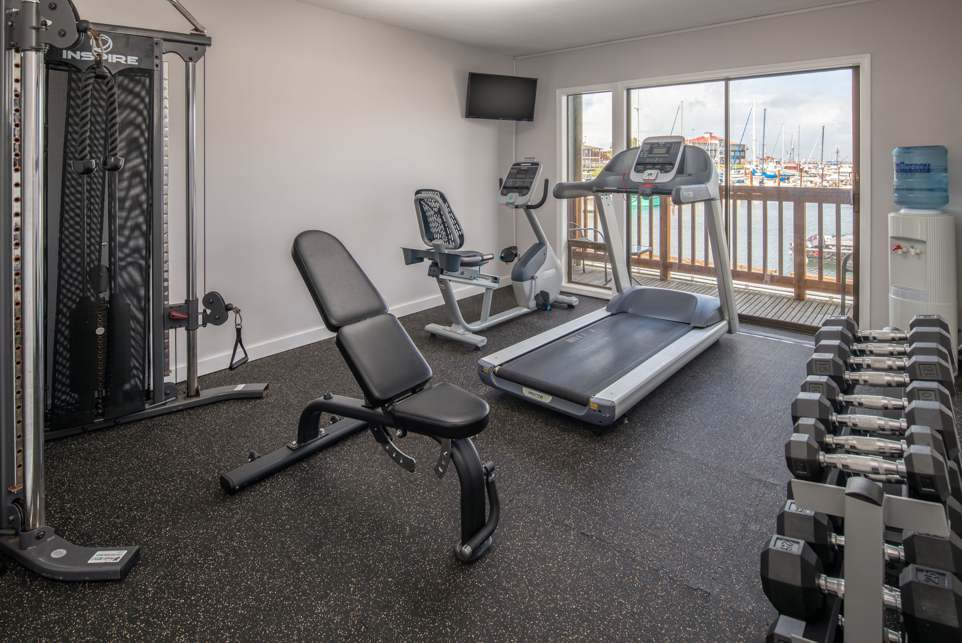 A gym with cardio machines, weight benches, and dumbbells.