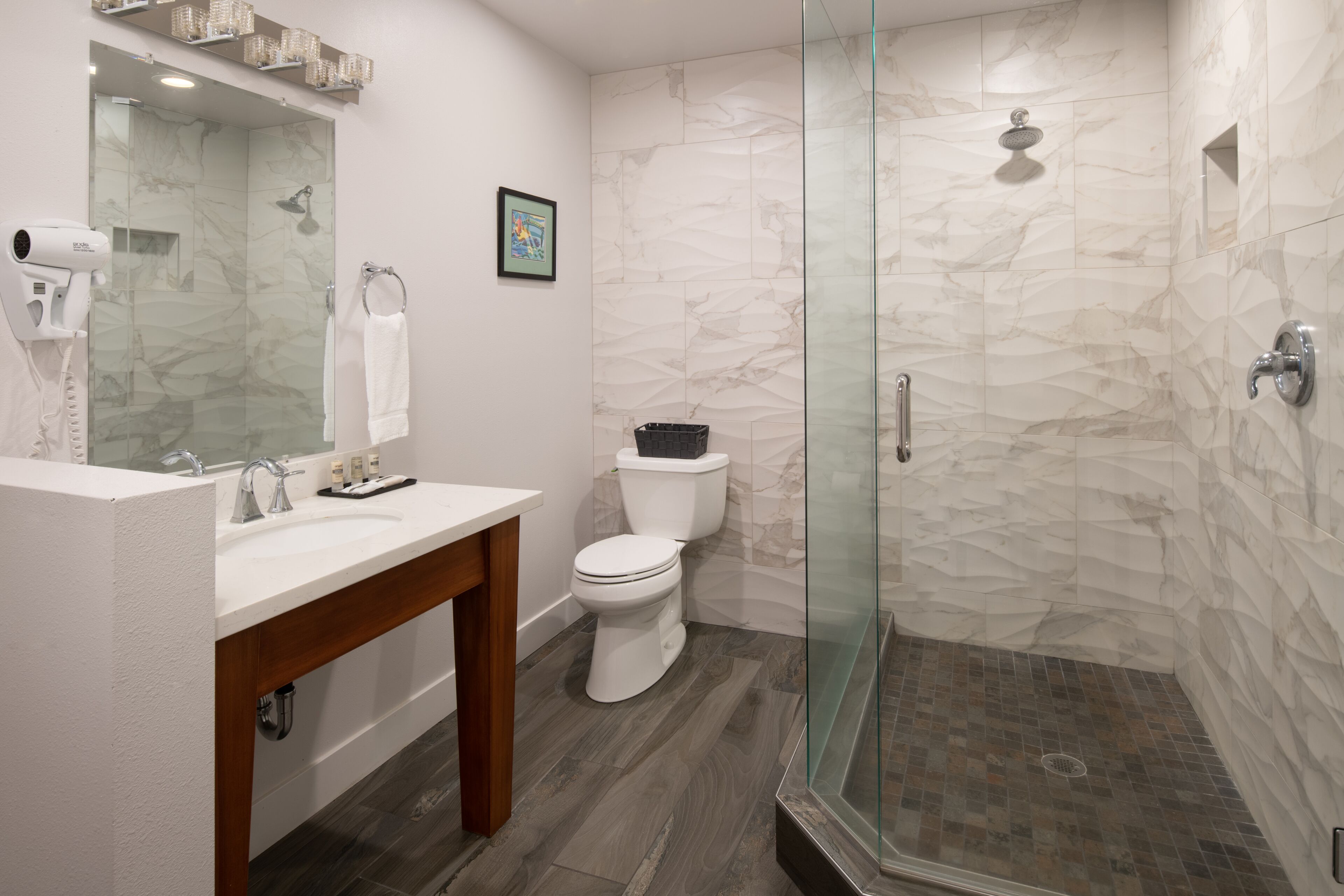 Un baño moderno con ducha de vidrio, lavamanos blanco y inodoro.