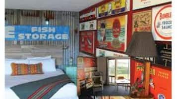 A hotel room with a bed, a desk, and a wall decorated with various posters and signs.