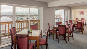 A dining area with a view of a marina, wooden furniture, and a large window.