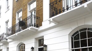 A row of white townhouses with black iron railings and a brick facade. - Sydney House Chelsea (London)