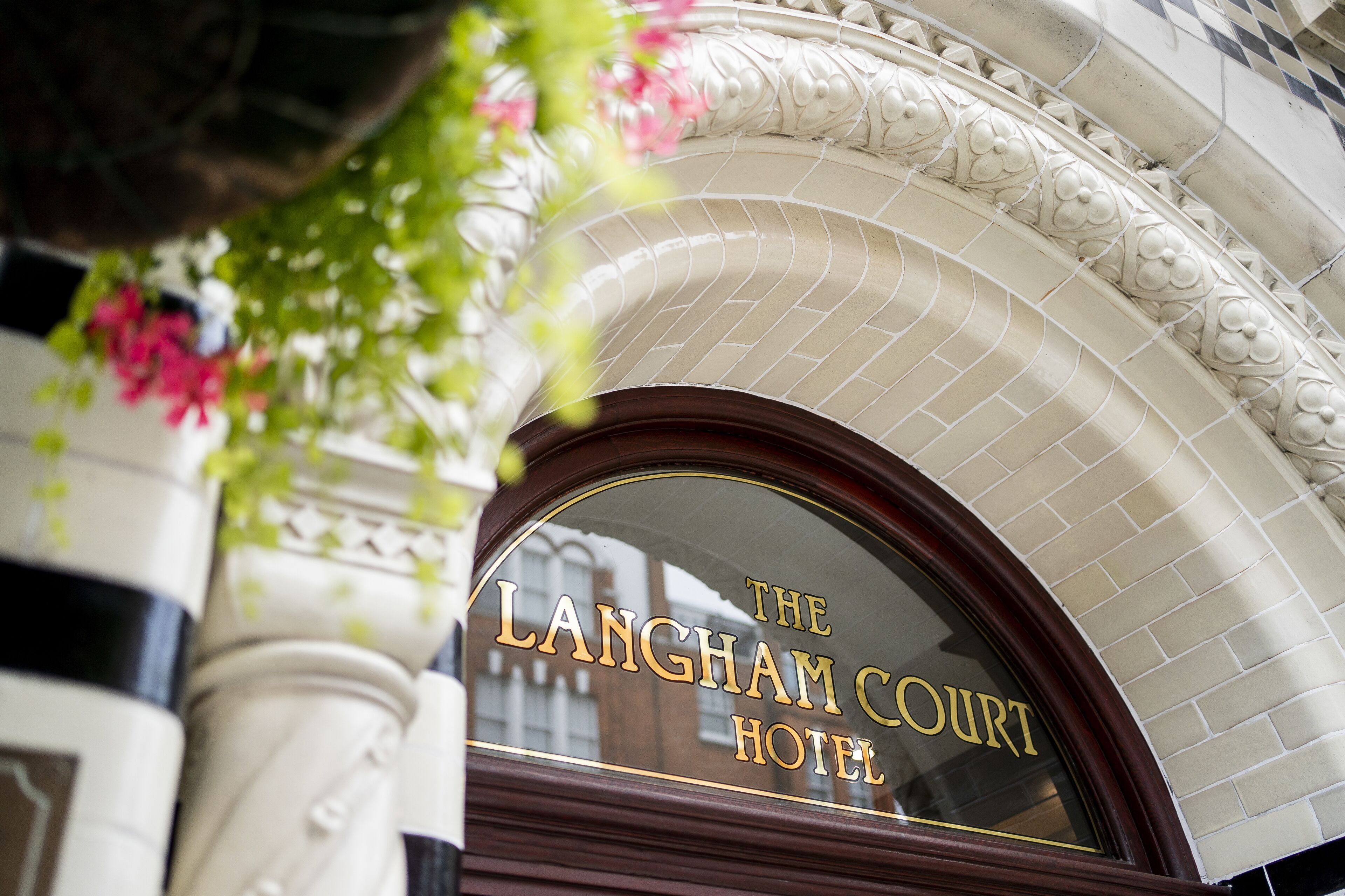 The entrance of The Langham Court Hotel with a decorative arch and a sign.