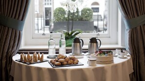 Una mesa de desayuno con pasteles, café y un florero junto a una ventana.