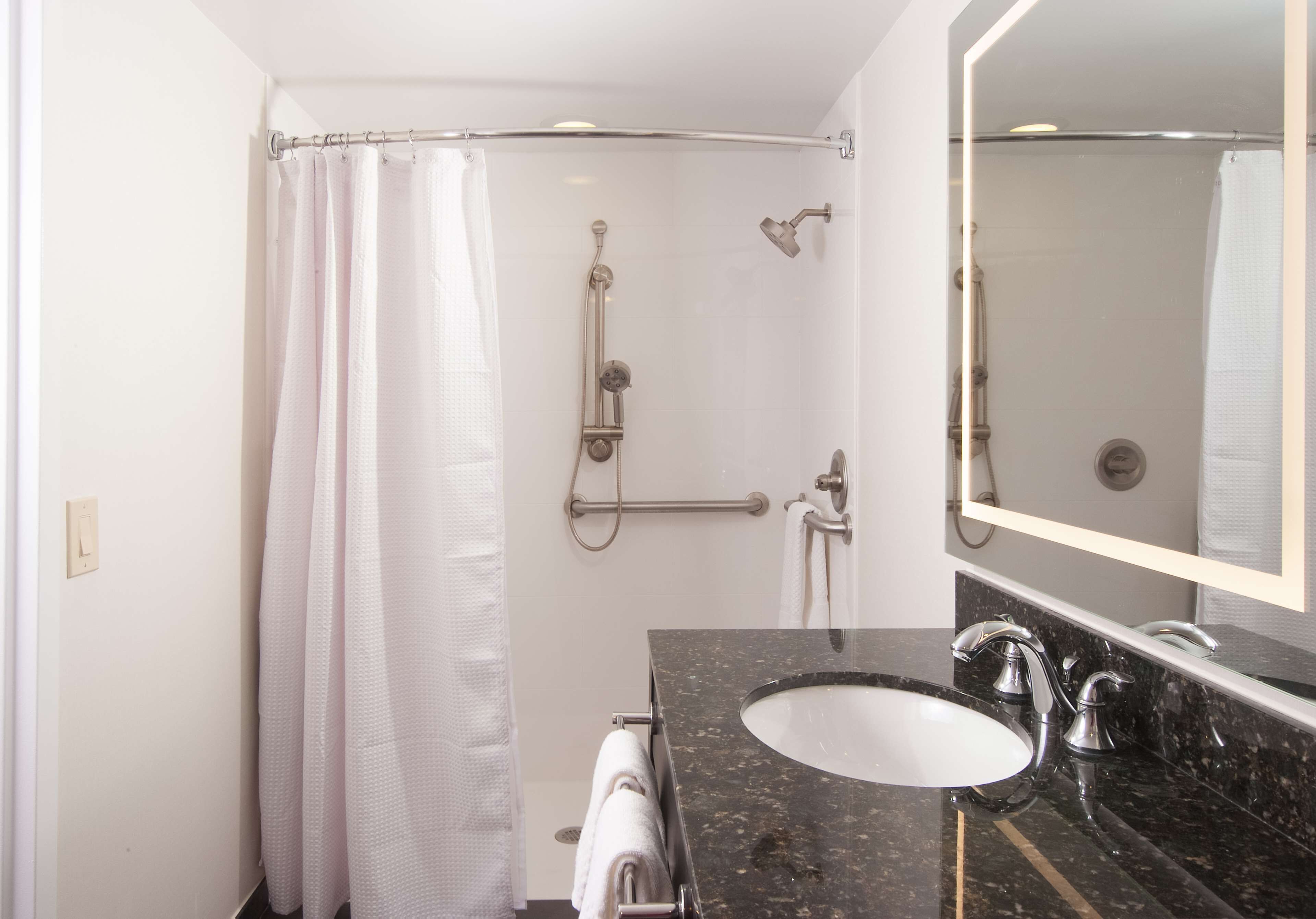 A bathroom with a shower, a sink, and a mirror.