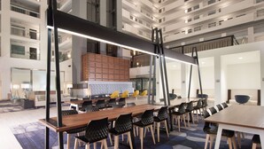 Une salle de conférence moderne, dotée d’une longue table, de chaises noires et d’une cloison en bois.