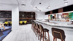 Un espace bar moderne doté d’un long comptoir, de tabourets de bar et d’une grande variété de bouteilles.