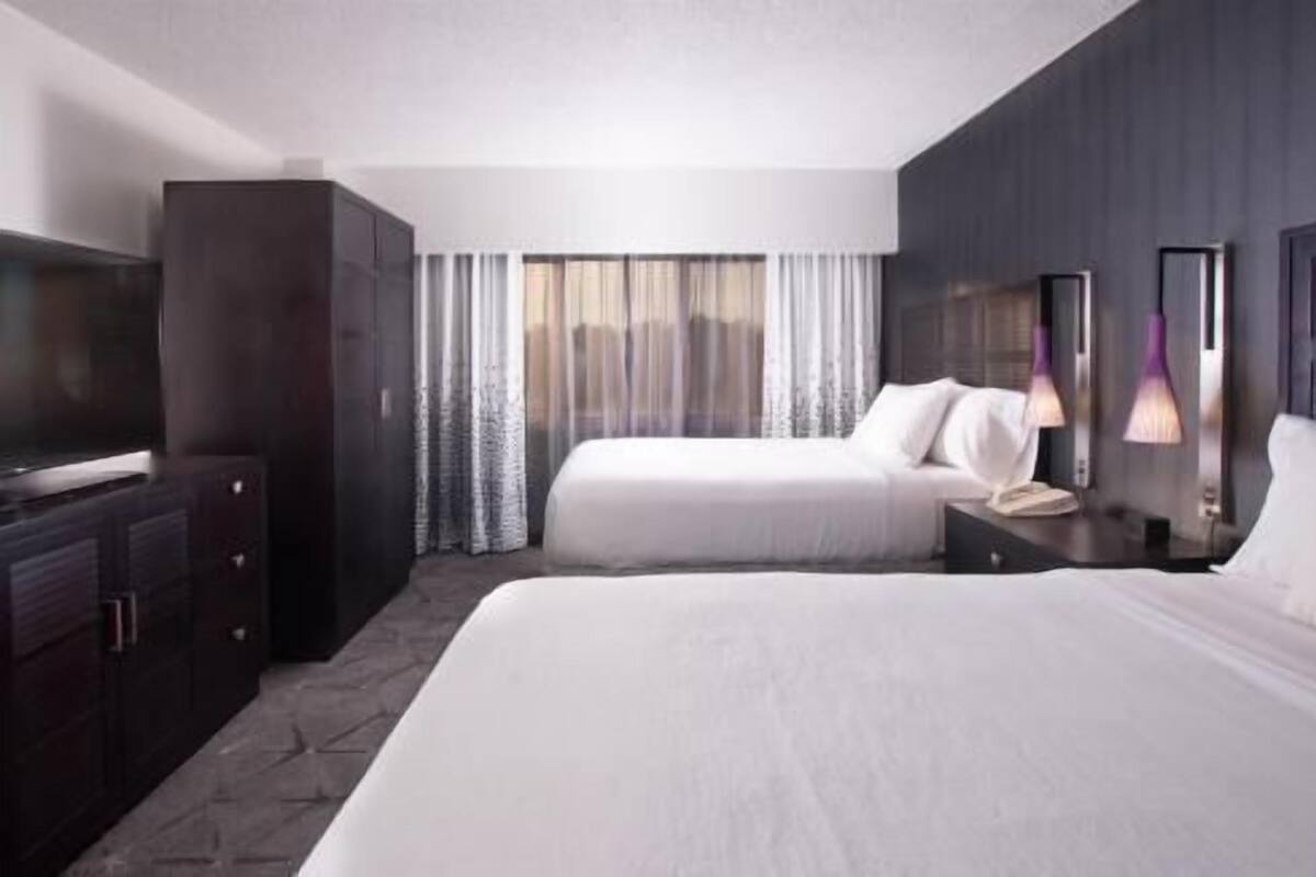 A hotel room with a large bed, a TV, a wardrobe, and a window with curtains.