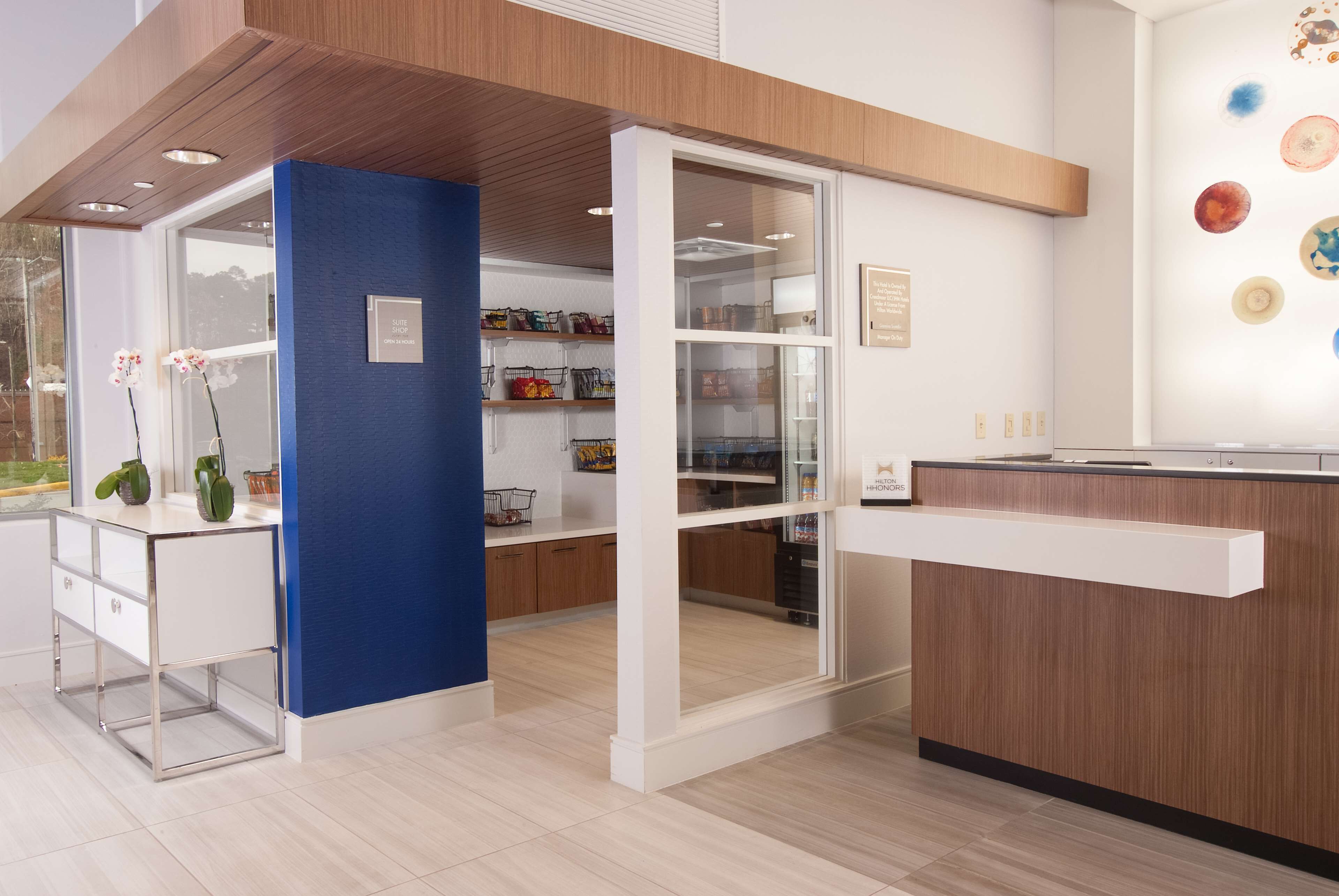 A modern reception area with a blue accent wall, a glass door leading to a storage room, and a wooden reception desk.