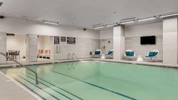 A swimming pool with clear water, surrounded by lounge chairs and a changing room.