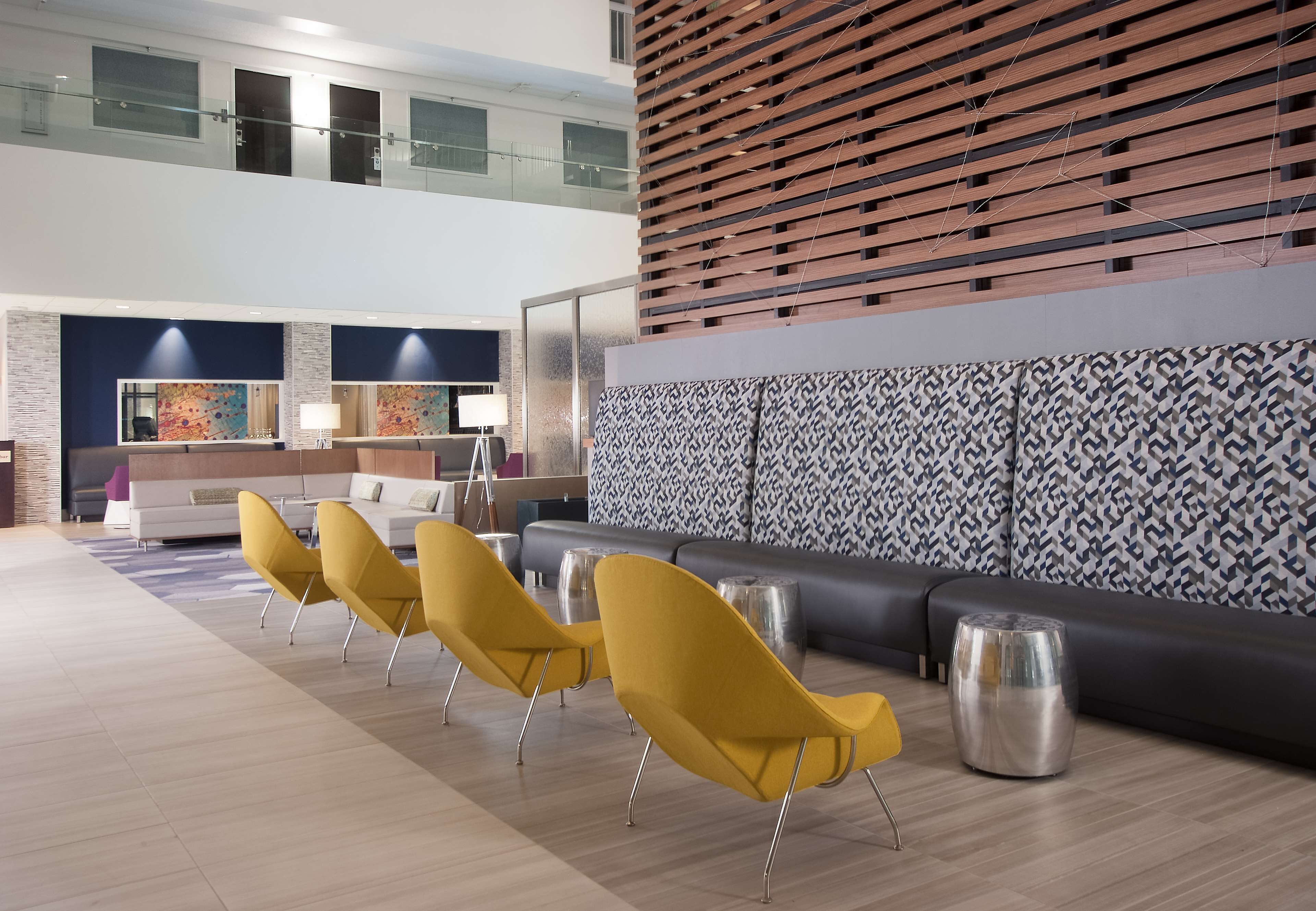 A modern lobby with a seating area, a reception desk, and a patterned wall.