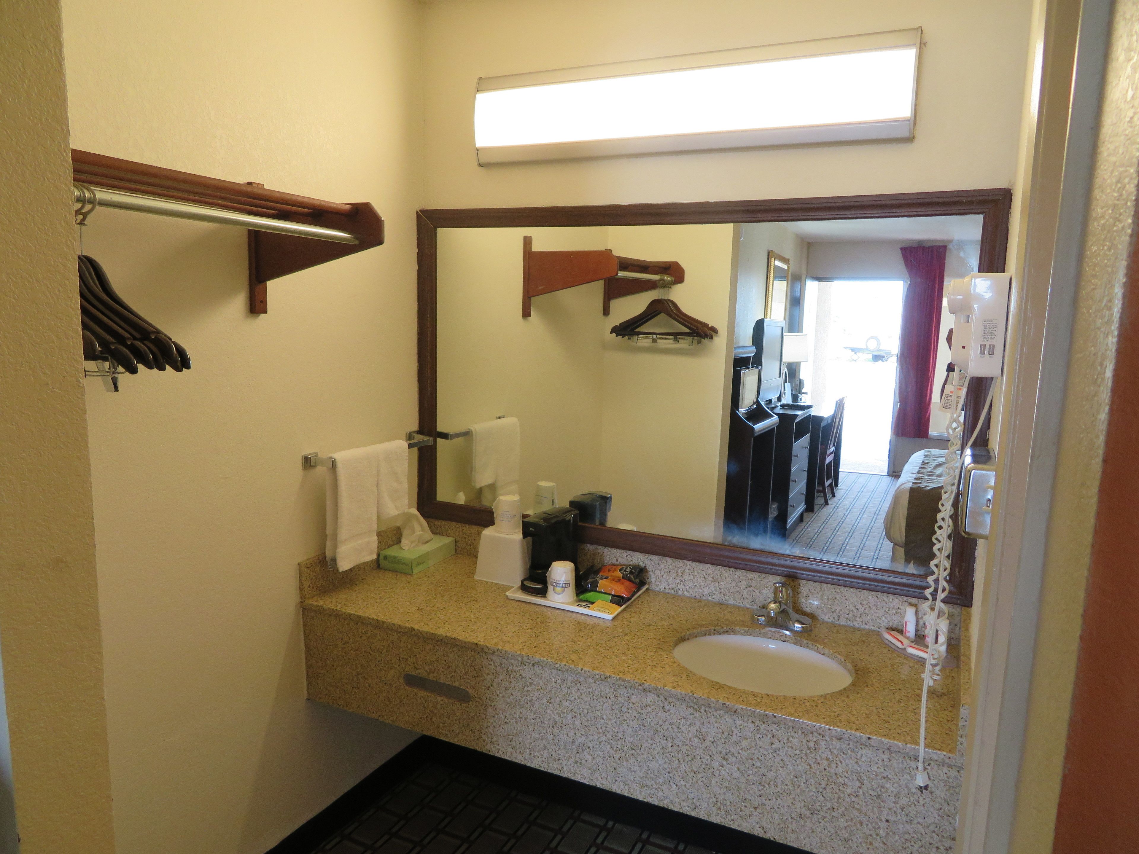 Une salle de bain équipée d’un lavabo, d’un miroir, d’un porte-serviettes et d’articles de toilette.