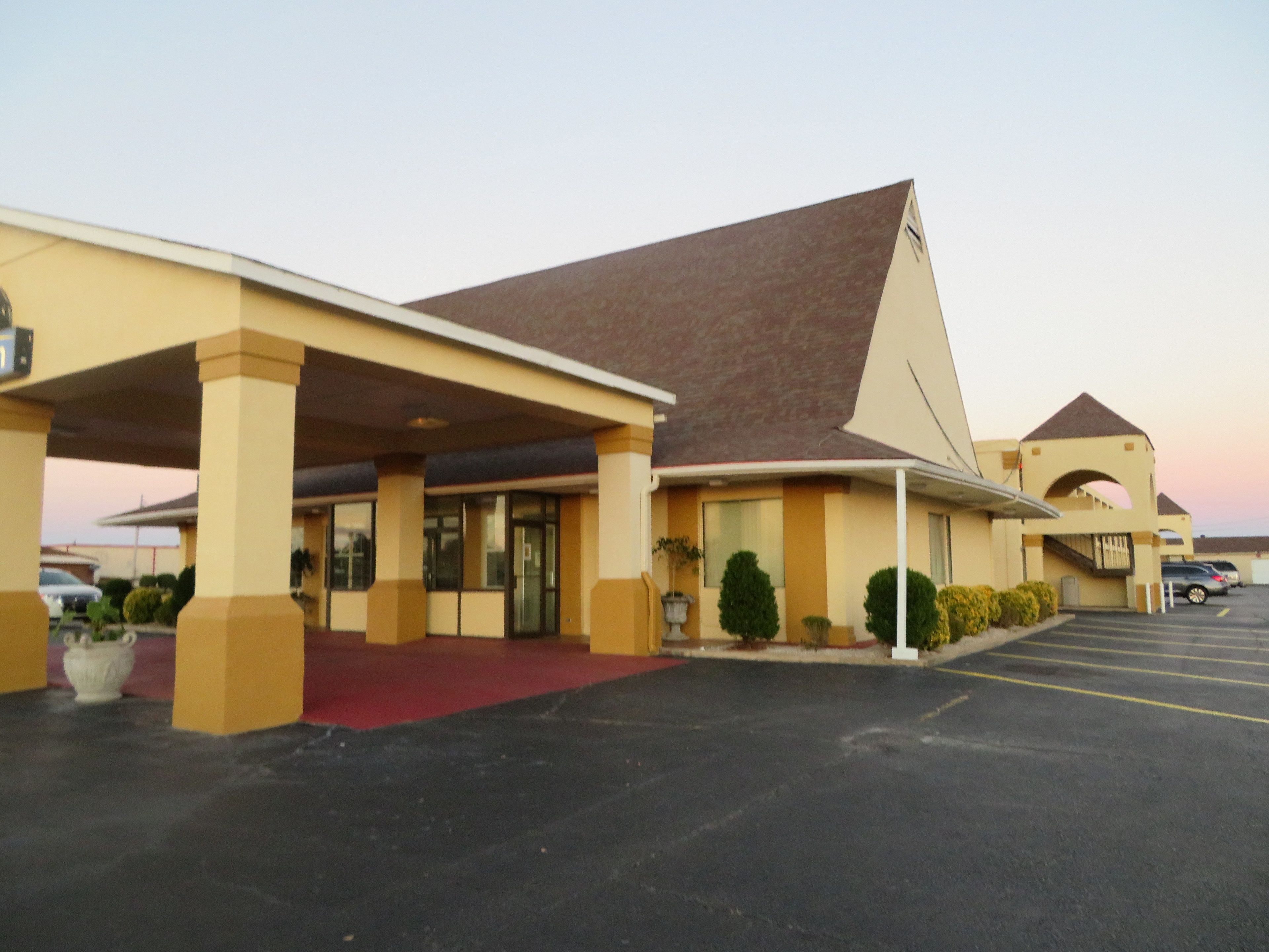 A motel with a red carpet entrance, a covered parking area, and a parking lot.