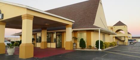 A motel with a red carpet entrance, a covered parking area, and a parking lot.
