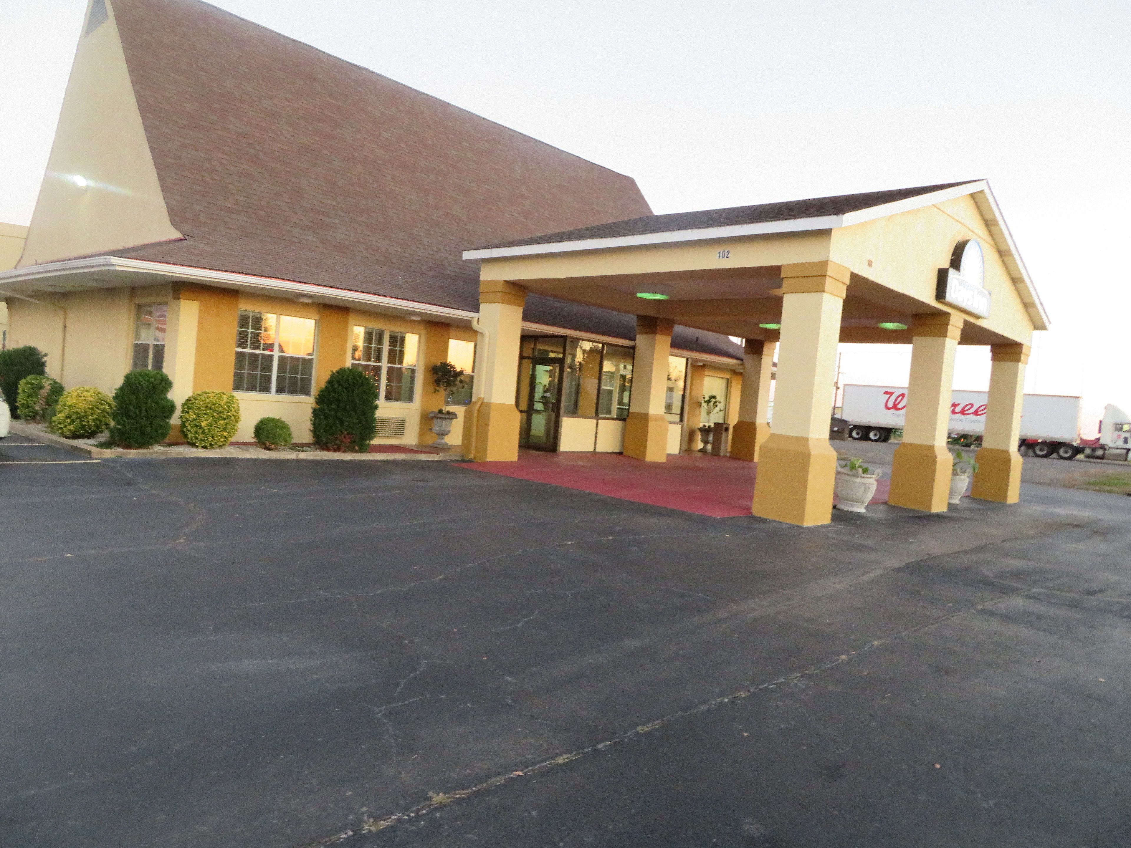 Un motel doté d’un grand parking, d’une entrée abritée et d’un toit à pente caractéristique.