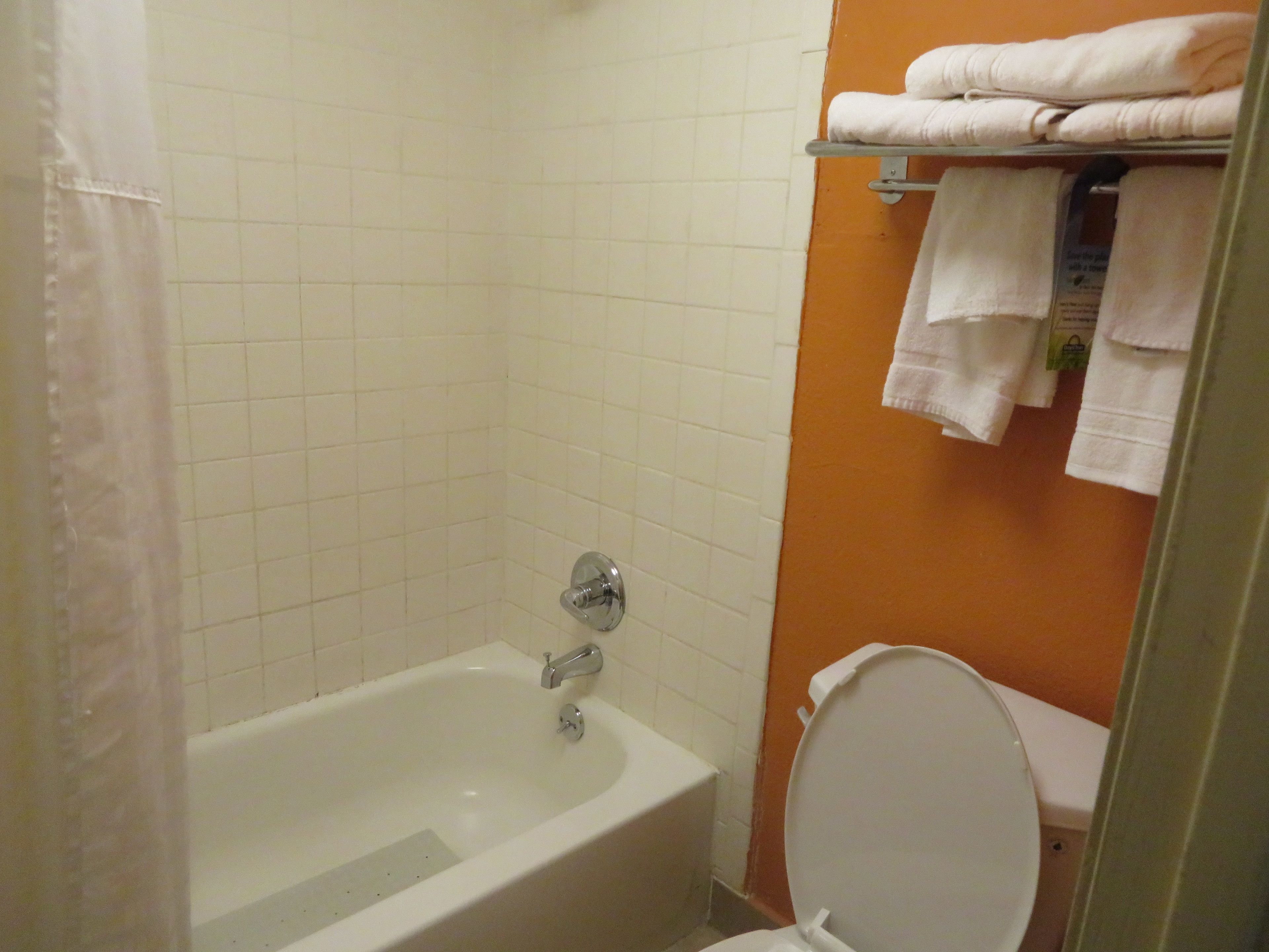 A bathroom with a bathtub, toilet, and a towel rack with folded towels.