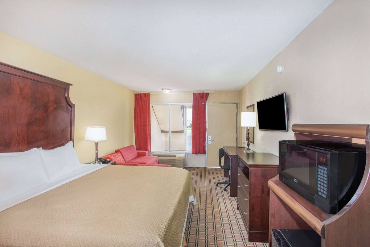 Een hotelkamer met een bed, een bureau, een televisie en een magnetron.
