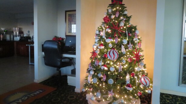 Un árbol de Navidad en el vestíbulo de un hotel, con un sombrero de copa, rodeado por un escritorio y una computadora.