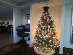 Un sapin de Noël dans le hall d’un hôtel, surmonté d’un haut-de-forme, entouré d’un bureau et d’un ordinateur.