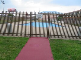 Zona de piscina cercada con un camino rojo que la conduce.