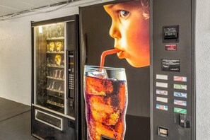 A beverage vending machine with a Coca-Cola and Sprite dispenser, a payment slot, and a change slot. - Econo Lodge Franklin - Springboro (Franklin)