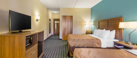 A hotel room with a TV, two beds, a desk, and a bathroom.