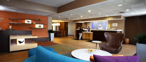 A lobby with a reception desk, seating area, and a dining space.