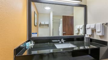 Une salle de bain moderne avec un grand miroir, un plan de toilette noir et un lavabo blanc.