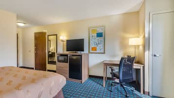 A hotel room with a bed, a desk with a chair, a television, a refrigerator, and a microwave.