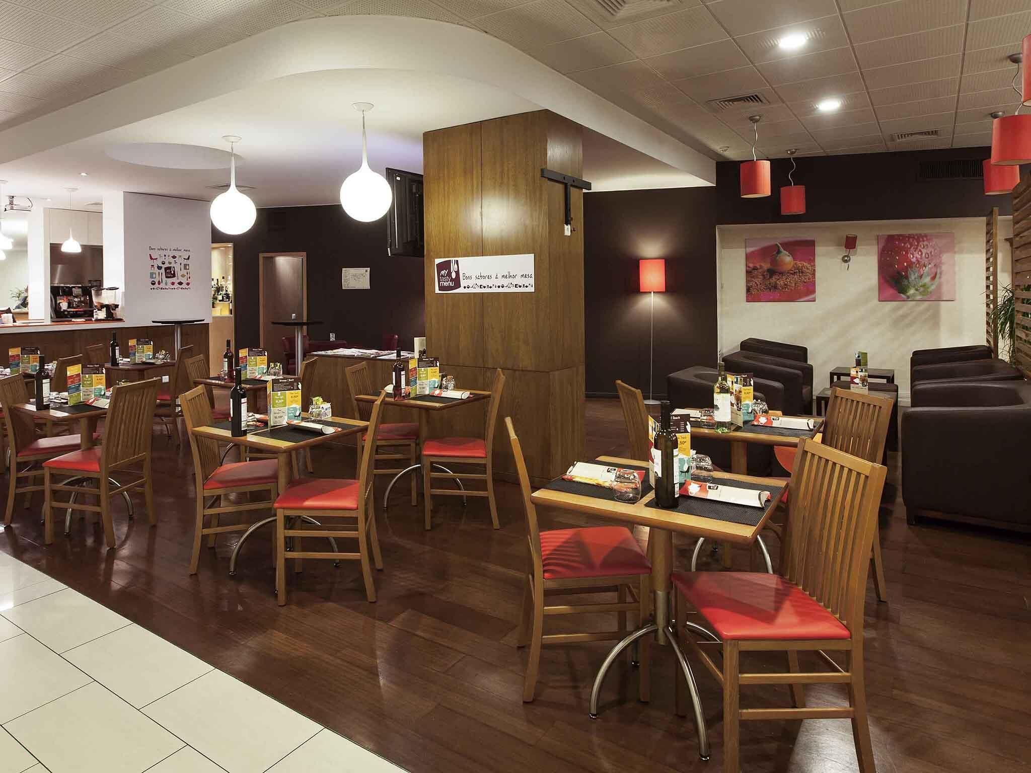 A restaurant interior with wooden tables and chairs, a bar area, and a seating section with sofas.