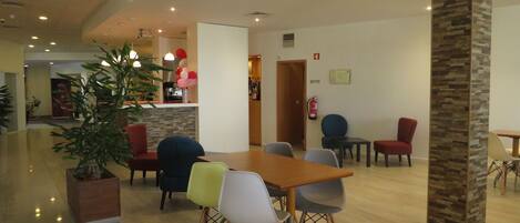 Un espace de salle à manger moderne avec une table et des chaises en bois, une plante en pot et un mur décoratif en pierre.