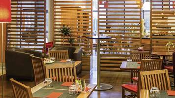 A restaurant with wooden partitions, tables with red cushions, and a modern interior design.
