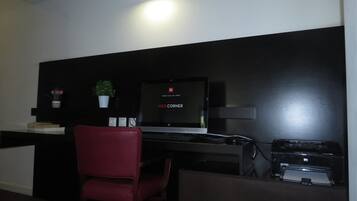 Una habitación de hotel con escritorio, computadora, impresora y una silla.