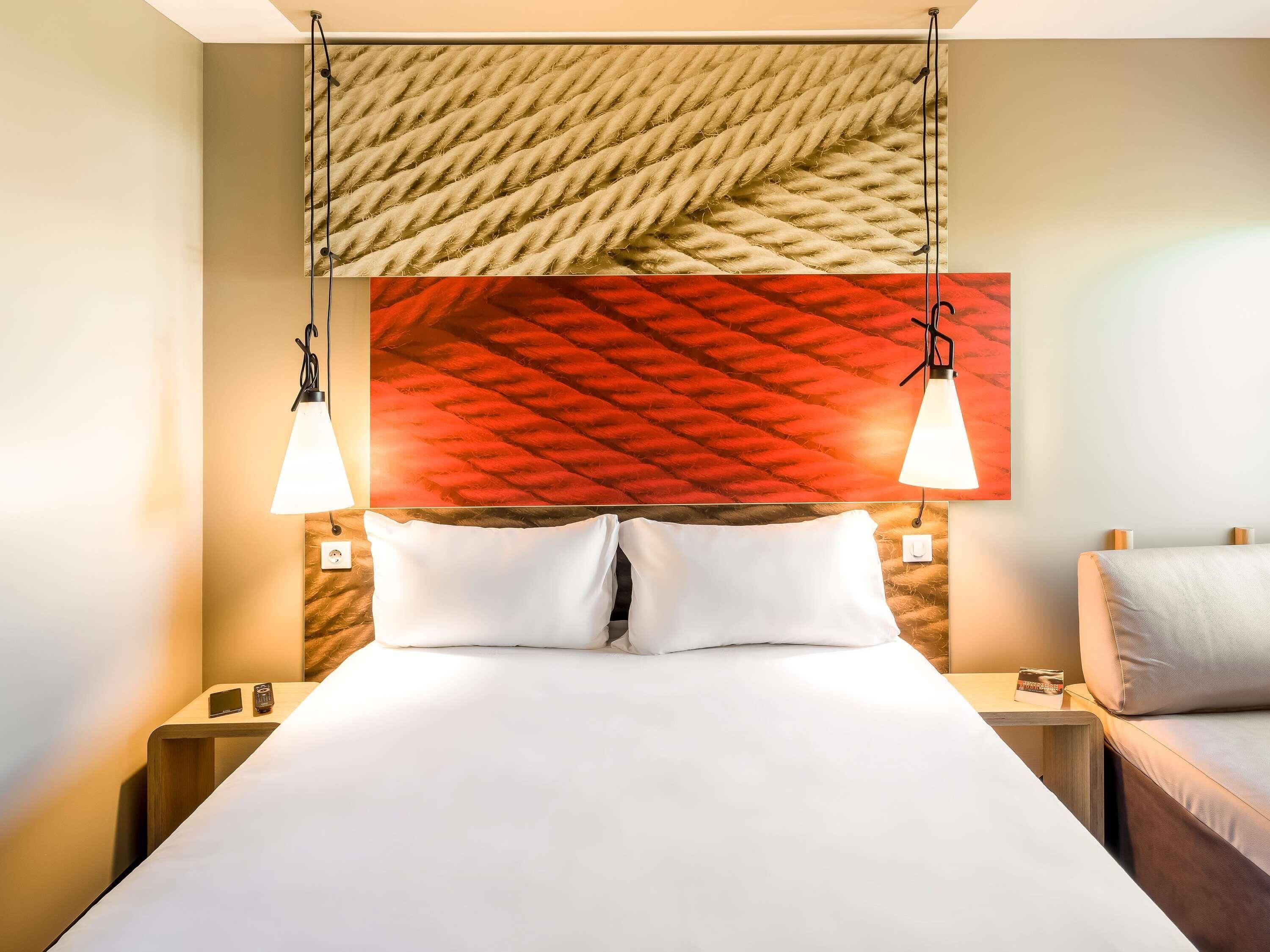 A neatly made bed with white linens, two bedside tables with lamps, and a textured wall above the bed.